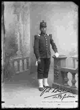 Foto de estudio de un soldado con uniforme francés que se encuentra  parado junto a la columna de un barandal