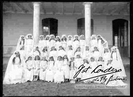 Grupo de niñas en el día de su primera comunión en el patio de un colegio