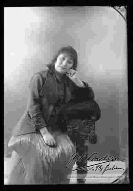 Foto de estudio de una dama que se encuentra sentada en un sillón.