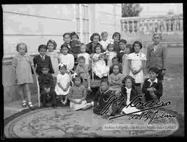 Grupo de niños y niñas junto a una dama en el patio de una casa particular