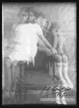Reproducción de una  imagen movida, Dos señoritas sentadas en una silla.