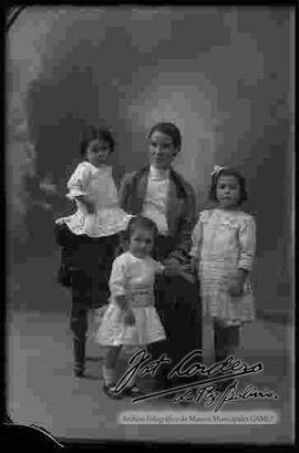 Una madre sentada en un sillón junto a sus tres hijas pequeñas,  foto de estudio de la familia.