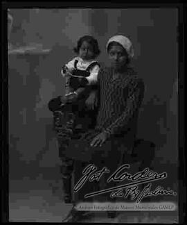 Foto de estudio de una dama sentada en un sillón junto a su hijo