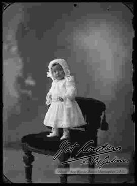 Foto de estudio de una niña pequeña, parada sobre un sillón