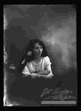 Foto de estudio de una dama que presenta un modelo de peinado para cabello largo, adornado con rosón.