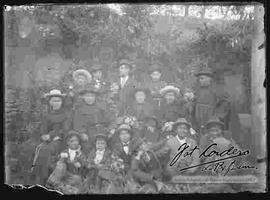 Sacerdotes franciscanos junto a unos niños y varones, en el huerto y patio de una casa particular