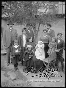 Grupo familiar, reunido en el patio de una casa particular, delante de un árbol