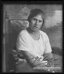 Reproducción de la fotografía de una dama que se encuentra sentada en una silla.
