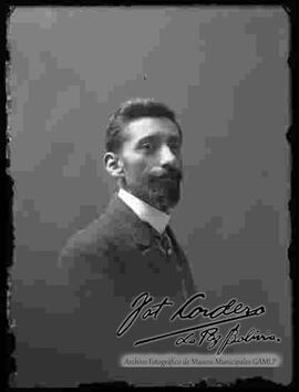 Foto de estudio de medio cuerpo de un varón de barba, vestido de traje