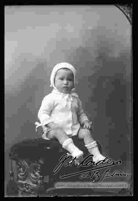 Foto estudio de una niña pequeña, sentada en la cabecera de un sillón