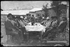 Grupo de cholas y varones, en una mesa compartiendo bebidas en carnavales.