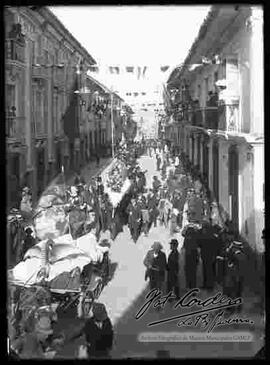 Desfile de istituciones por las fiestas patrias del 6 de agosto, donde se puede apreciar una carrosa, tirada por caballos, que lleva la imagen de la madre patria y detras a personal de instituciones como ser la Sociedad de Socorros Mutuos.