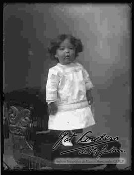 Foto de estudio de una niña pequeña, parada encima de un sillón