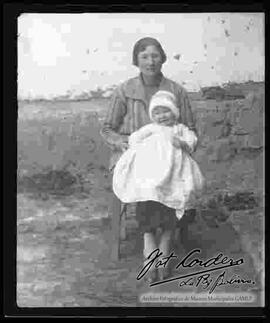 Imagen de una vecina de provincia, sentada en una silla, sujetando un bebe, para realizar tramites