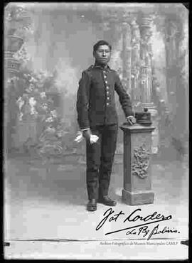 Foto de estudio de un soldado con uniforme francés, parado y apoyado a una pequeña columna