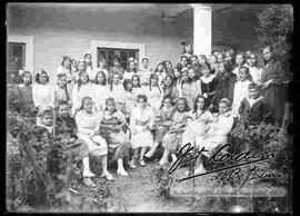 Grupo de señoritas estudiantes, posando en el patio de un colegio. Entre ellas se encuentran dos niños