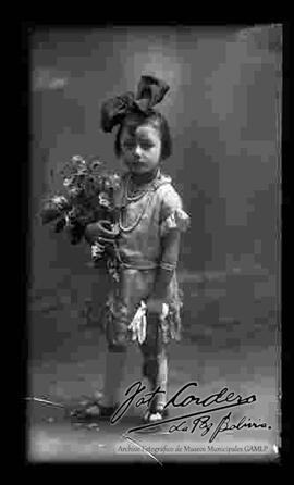 Foto de estudio de una niña sosteniendo flores y unos guantes en la mano izquierda