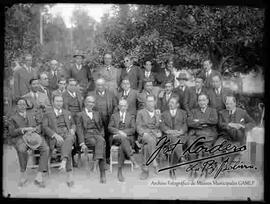 Grupo de varones y  empleados de una  empresa, reunidos en el jardín de una casa particular