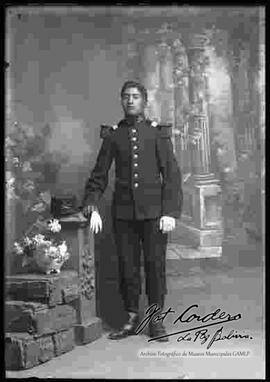 Foto de estudio de un soldado, parado y apoyado con la mano derecha a una pequeña columna