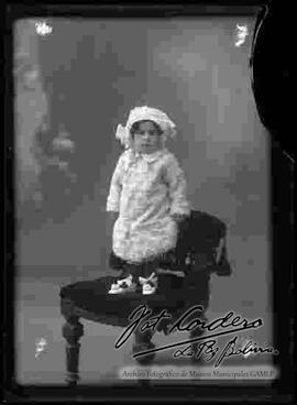 Foto de estudio de una niña pequeña que se encuentra parada sobre un sillón