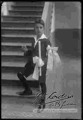 Un niño del colegio San Calixto el día de su primera comunión parado en unas gradas. 21 de junio de 1927