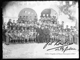 Niños de la Escuela de la Tercera Orden de San Francisco, en el día de su primera comunión, junto a dos curas en el patio del convento de San Francisco