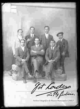 Foto de estudio de un grupo de siete varones vestidos de traje.