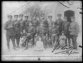 Reproducción de la fotografía de un grupo de oficiales y soldados del regimiento de caballería en el patio de un cuartel junto a tres niñas