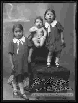 Foto de estudio de tres hermanitos. Dos niñas y un bebe