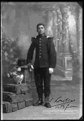 Foto de estudio de un soldado, parado y apoyado con la mano derecha a una pequeña columna