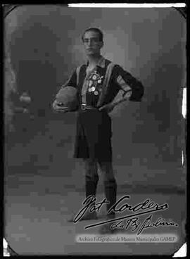 Foto de estudio de un futbolista con medallas, sosteniendo un balón