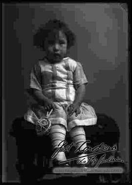Foto de estudio de una niña pequeña, sentada encima de un sillón
