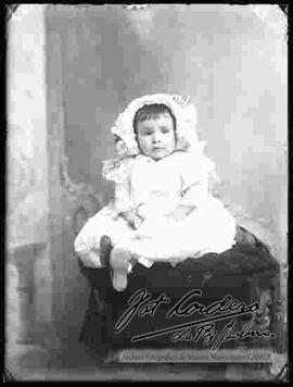 Foto de estudio de una bebe sentada en la cabecera de un sillón