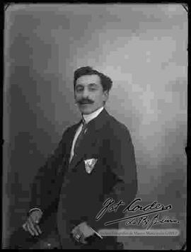Foto de estudio de un varón que viste de traje y que presenta un modelo de peinado.