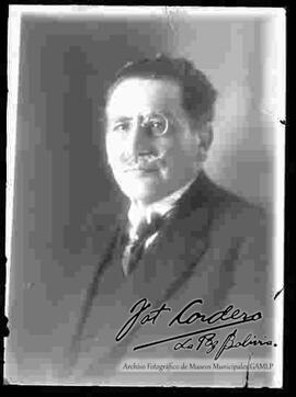 Reproducción de la fotografía de un varón de lentes y que viste de traje