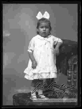 Foto de estudio de una niña pequeña, parada encima de un sillón