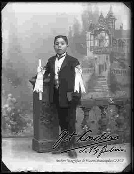 Foto de estudio de un niño, en el día de su primera comunión, junto a una pequeña columna