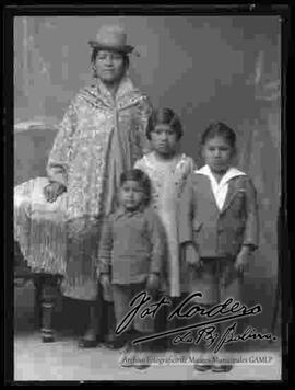 Foto de estudio de una familia. Una dama junto a sus tres hijos