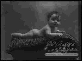 Foto de estudio de una bebe desnuda y recostada encima de una manta
