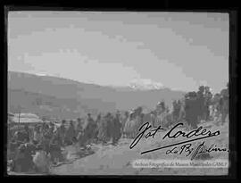 Grupo de mujeres y hombres campesinos subiendo, al alto con el fondo del Illimani