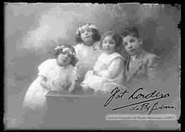 Foto de estudio con esfumador de cuatro niños (hermanitos). Un niño y tres niñas vestidas de blanco