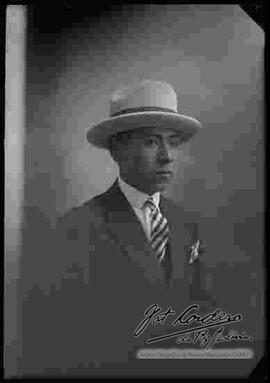 Foto de estudio de medio cuerpo de un varón de traje y sombrero.