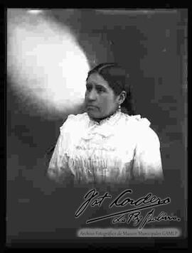 Foto de estudio del busto de una chola que no lleva sombrero. Viste una blusa cerrada manga larga