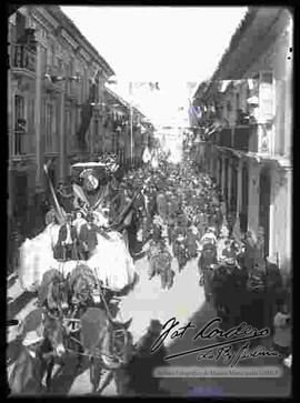 Desfile por las fiestas  patrias del 6 de agosto, donde se puede ver  una carrosa con niños adornada, con la imagen de un ángel y tirada por mulas por la calle Mercado.