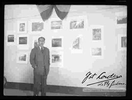 Julio Cordero Ordoñez, posando delante de las fotografías de exposición "Foto Cordero Jiménez", en el salón de la cancillería. octubre de 1948.