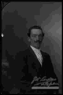 Fotografía de estudio. Imagen de medio cuerpo de un varón con bigote.