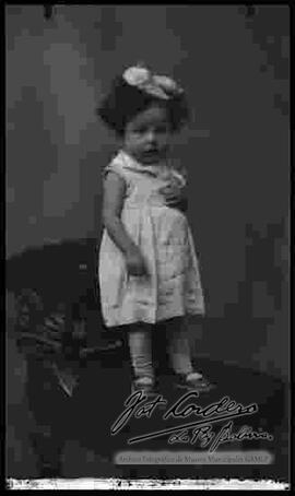 Foto de estudio de una niña pequeña, parada encima de un sillón