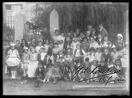 Niños y niñas estudiantes, disfrazados y posando afuera de una escuela