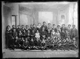 Foto de estudio de grupo de niños de un colegio, junto a su profesor en el interior de un salón