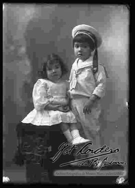 Foto de estudio de una niña y un niño (hermanitos), encima de un sillón